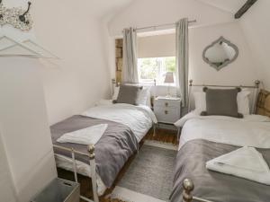 two twin beds in a room with a window at Thimble Cottage in Cheltenham