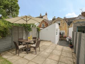 a patio with a table and chairs and an umbrella at Thimble Cottage in Cheltenham