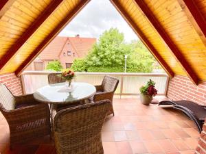 d'une terrasse avec une table, des chaises et une fenêtre. dans l'établissement Ferienhaus Antje Greetsiel Nordsee, à Krummhörn