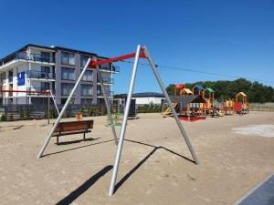 - une balançoire sur une plage avec une aire de jeux dans l'établissement Prywatne apartamenty w hotelu - 365PAM, à Sarbinowo