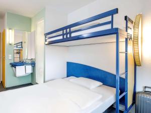 1 Schlafzimmer mit 2 Etagenbetten und einem Spiegel in der Unterkunft Ibis budget Hannover Hbf in Hannover