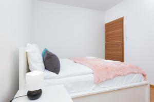 a white bedroom with a bed and a dresser at Apartments Platynowa Gdańsk by Renters in Gdańsk