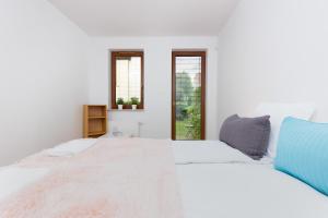 a white bedroom with a large bed and two windows at Apartments Platynowa Gdańsk by Renters in Gdańsk