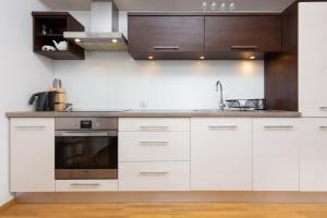a kitchen with white cabinets and a sink at Apartments Platynowa Gdańsk by Renters in Gdańsk