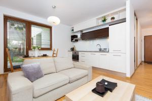 a living room with a couch and a kitchen at Apartments Platynowa Gdańsk by Renters in Gdańsk