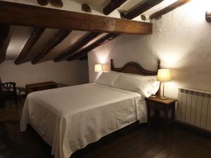 um quarto com uma cama branca e uma mesa com um candeeiro em Hotel Labranza em San Martín de Valdeiglesias