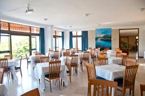 a restaurant with white tables and chairs and windows at Hotel Europa in Ispra