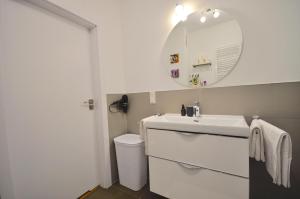 W białej łazience znajduje się umywalka i lustro. w obiekcie Apartament harmonic aparts w Polanicy Zdroju