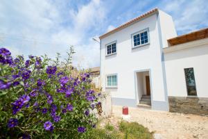 una casa blanca con flores púrpuras delante de ella en Ardmar B&B en Vila do Bispo