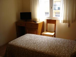 1 dormitorio con 1 cama, TV y ventana en Pio V, en Vigo