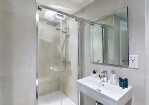 a white bathroom with a sink and a shower at Deluxe Central London North Apartment in London