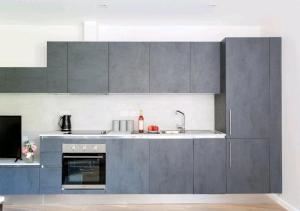 eine Küche mit grauen Schränken und einer Spüle in der Unterkunft Deluxe Central London North Apartment in London