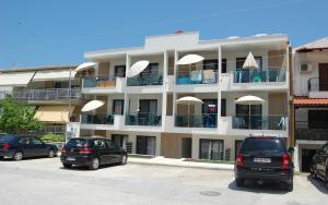 a white apartment building with cars parked in a parking lot at Sarti Holidays in Sarti