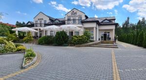 a large white building with umbrellas on a street at Hotel - Restauracja Koral in Wieliczka