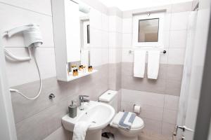 a white bathroom with a sink and a toilet at Skourtis Apartments in Eleonas