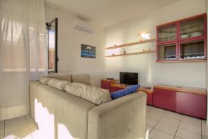 een woonkamer met een bank en een televisie bij SUNSET GREG - fronte mare San Gregorio by LoveSud in Leuca