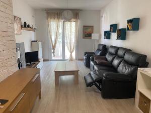 a living room with a black leather couch and a table at Appartamento Elegance in Lignano Sabbiadoro
