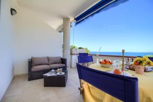 een woonkamer met een tafel, stoelen en een bank bij SUNSET GREG - fronte mare San Gregorio by LoveSud in Leuca