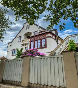 una casa bianca dietro una recinzione con fiori viola di Norrehus a Klippan