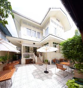 曼谷Baan Dinso的一座带露台的建筑,配有桌子和遮阳伞
