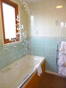 baño con bañera, lavabo y ventana en The Ferry Boat Inn en Ullapool