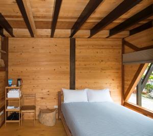 成功的住宿－三仙台比西里岸營地/渡假小木屋，木制客房内的一间卧室,配有一张床