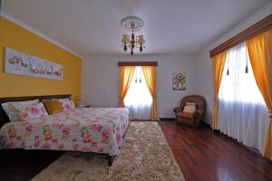 sypialnia z łóżkiem, krzesłem i oknami w obiekcie Ponta do Sol Villa w mieście Ponta do Sol