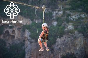a person on a zip line over a mountain at Albergo Diffuso Bacco Furore in Furore