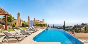 una piscina con sillas y sombrillas junto a un edificio en Resitour - Perneri Four Bedroom Villa, en Pafos