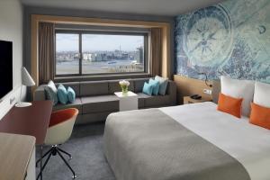 a hotel room with a bed and a couch and a window at Mövenpick Hotel Amsterdam City Centre in Amsterdam +93 photos