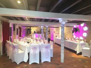 a banquet hall with white tables and chairs and purple lighting at Moulin de Moulignon B&B in Messy