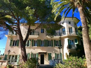 um grande edifício branco com persianas verdes e palmeiras em VTF Clairefont em Bandol