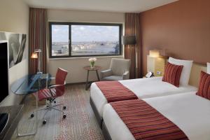 une chambre d'hôtel avec un lit, un bureau et une fenêtre dans l'établissement Mövenpick Hotel Amsterdam City Centre, à Amsterdam