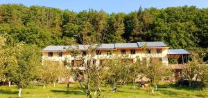 a house in the middle of a field with trees at Restland Dilijan Family Hotel in Dilijan