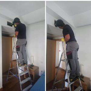 um homem numa escada a pintar um quarto em Bi Hotel em Porto Ercole