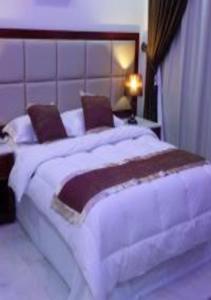 a bedroom with a large white bed with pillows at Ashbilia Suites in Al Khobar
