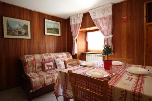 a dining room with a table and a couch at Lo Stambecco Holiday Apartment - Affitti Brevi Italia in Brusson +14 photos