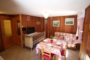 uma sala de jantar com mesa e cadeiras e uma televisão em Lo Stambecco Holiday Apartment - Affitti Brevi Italia em Brusson