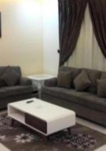 a living room with a couch and a coffee table at Ashbilia Suites in Al Khobar