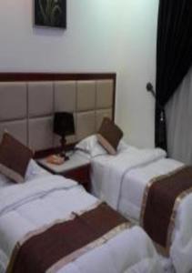 a hotel room with two beds and a table at Ashbilia Suites in Al Khobar