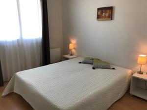 a bedroom with a large white bed with two lamps at Les Palmiers in Saint-Cyr-sur-Mer