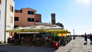 a group of people sitting at a restaurant under umbrellas at Apartments ELA in Piran