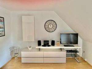 クルムホルンにあるFerienhaus Antje Greetsiel Nordseeの白いエンターテイメントセンター(テレビと時計付)