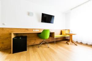 a living room with a green chair and a television at Hotel zur Post in Heilbronn