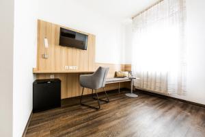 a room with a chair and a desk and a television at Hotel zur Post in Heilbronn