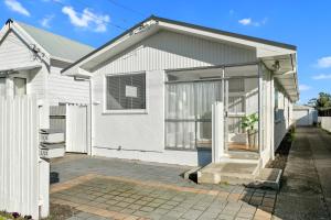 a white house with glass doors and a driveway at Coastal City Retreat - New Brighton Accommodation in Christchurch