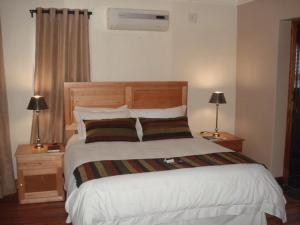 a bedroom with a large white bed with two lamps at Uitsigpark Guest@home4U in Centurion