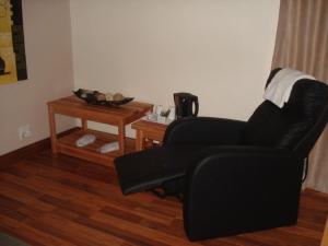a living room with a black chair and a table at Uitsigpark Guest@home4U in Centurion