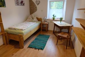 a bedroom with a bed and a table and a window at Biohof Grissenberger in Abetzdorf