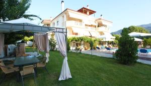 un patio con una mesa y una sombrilla y un edificio en Villa Valeria Thassos, en Limenas